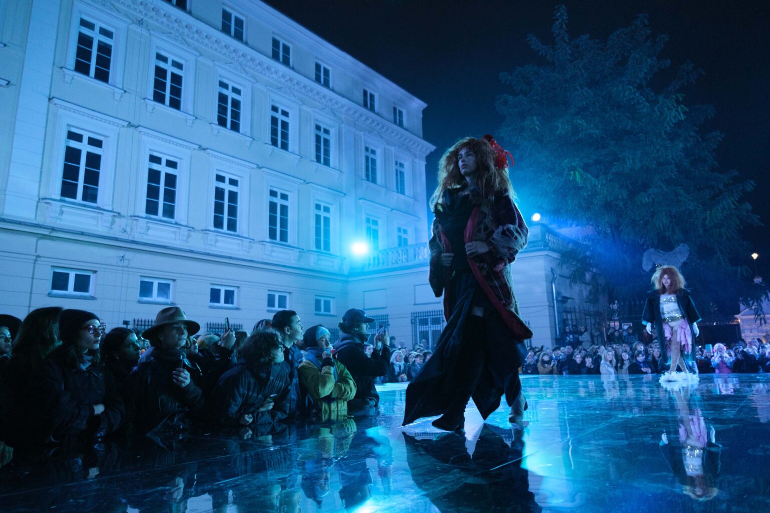 modelka na wybiegu, niebieskie światło, budynek w tle