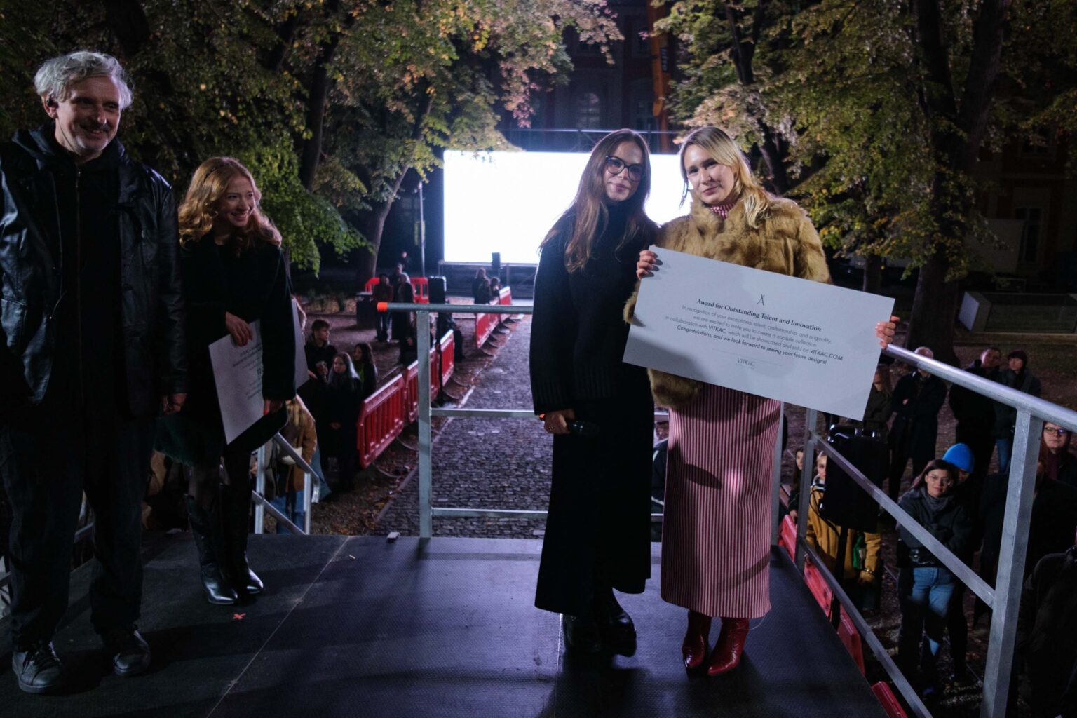 dwie kobiety pozują do zdjęcia, jedna trzyma w ręku dużą informację o nagrodzie