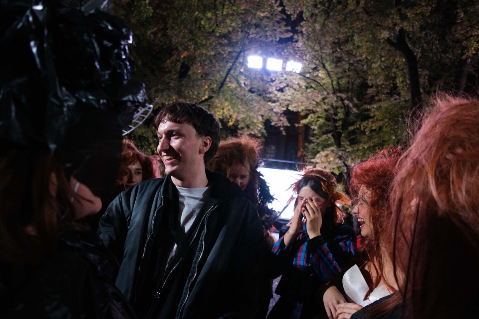 Uśmiechnięty młody mężczyzna, w tle uradowane osoby