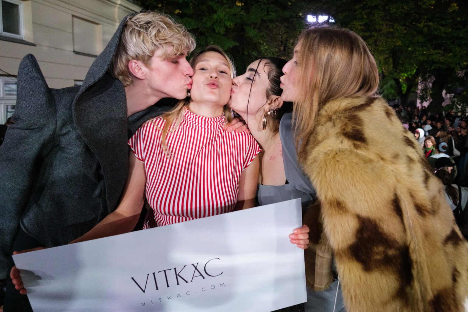 modele i modelku całują w policzki młodą kobietę