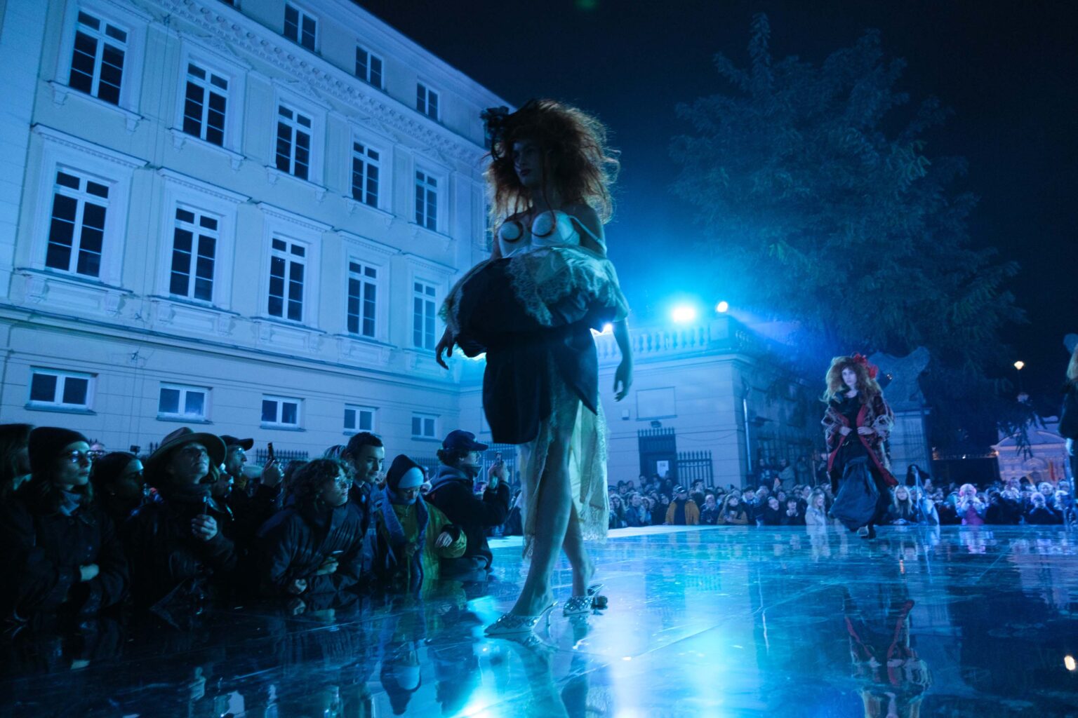 modelka na wybiegu, niebieskie światło, budynek w tle