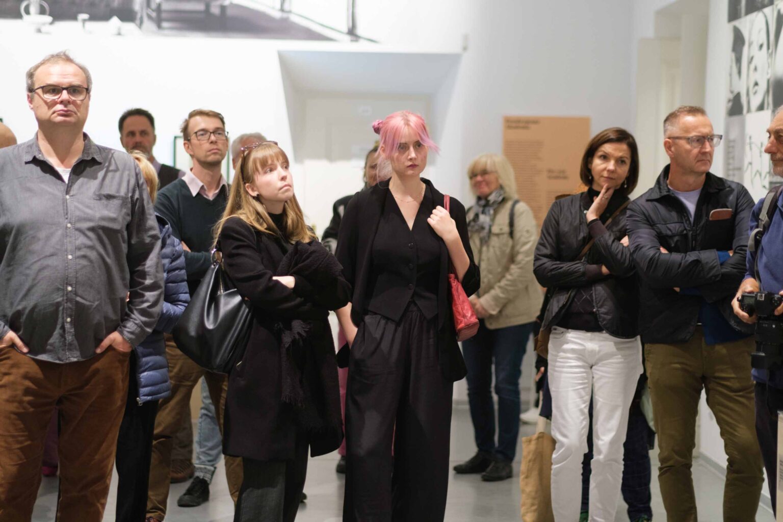 grupa zwiedzająćych w przestrzeni wystawy