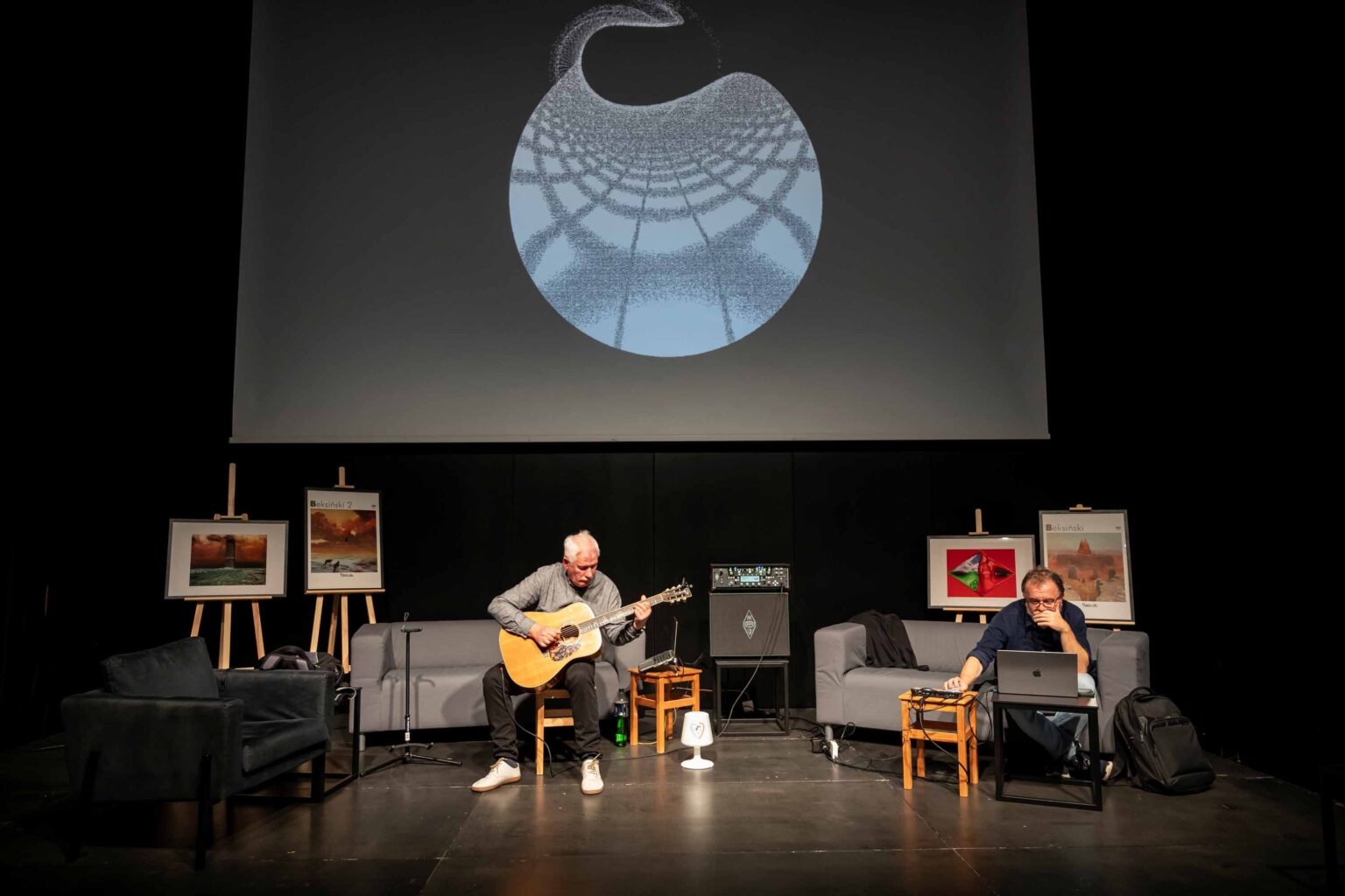 Dwaj mężczyźni na scenie. Jeden z nich gra na gitarze