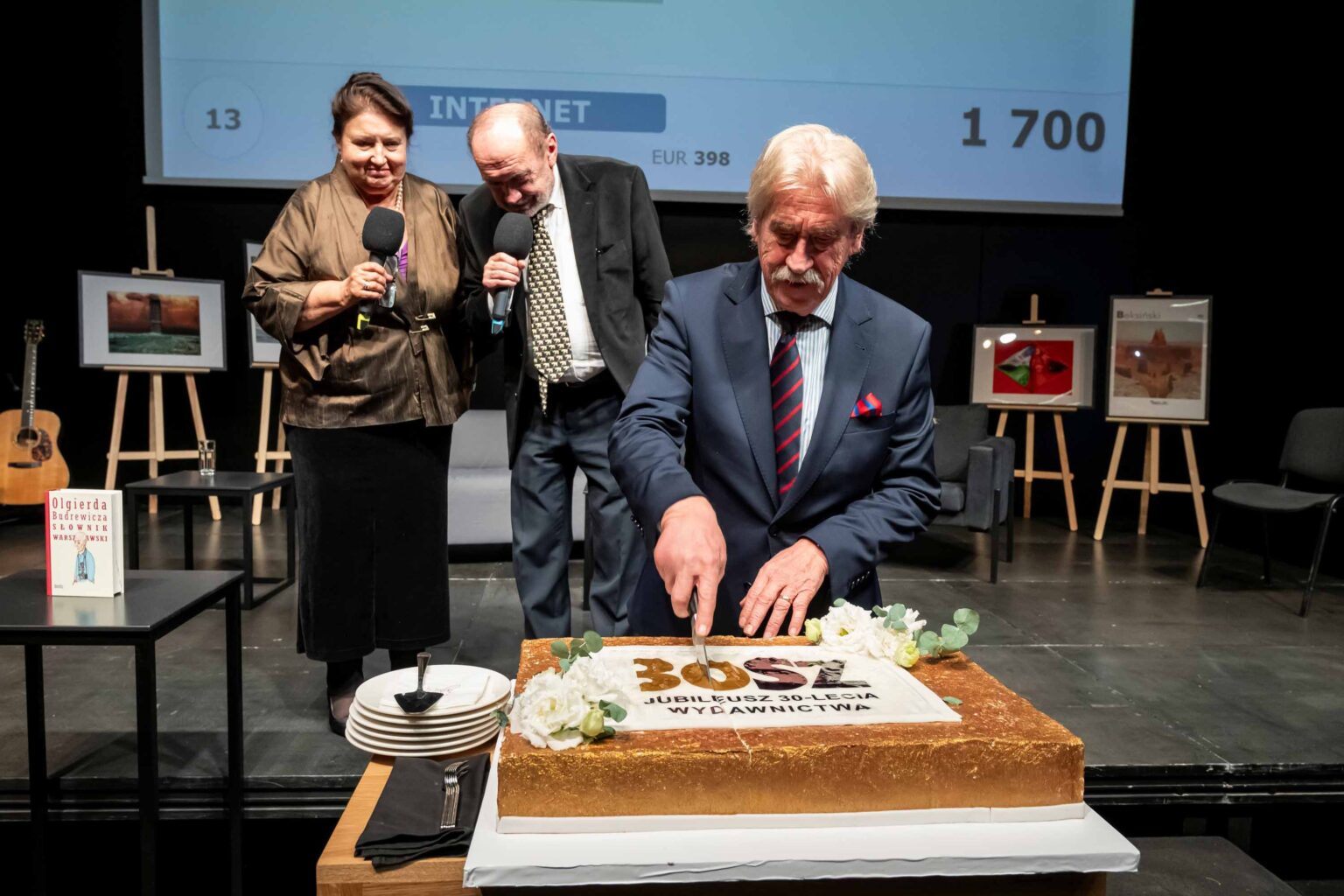 Mężczyzna w garniturze kroi tort