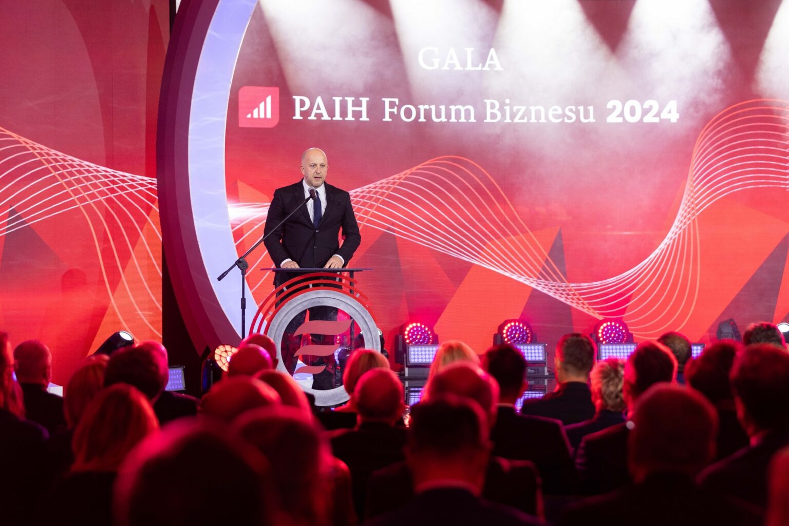 mężczyzna w garniturze przemawia do dużej grupy osób na widowni