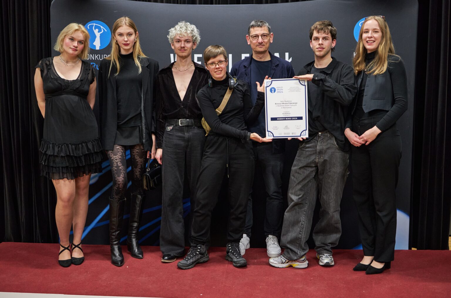 Grupa osób na scenie prezentuje dyplom