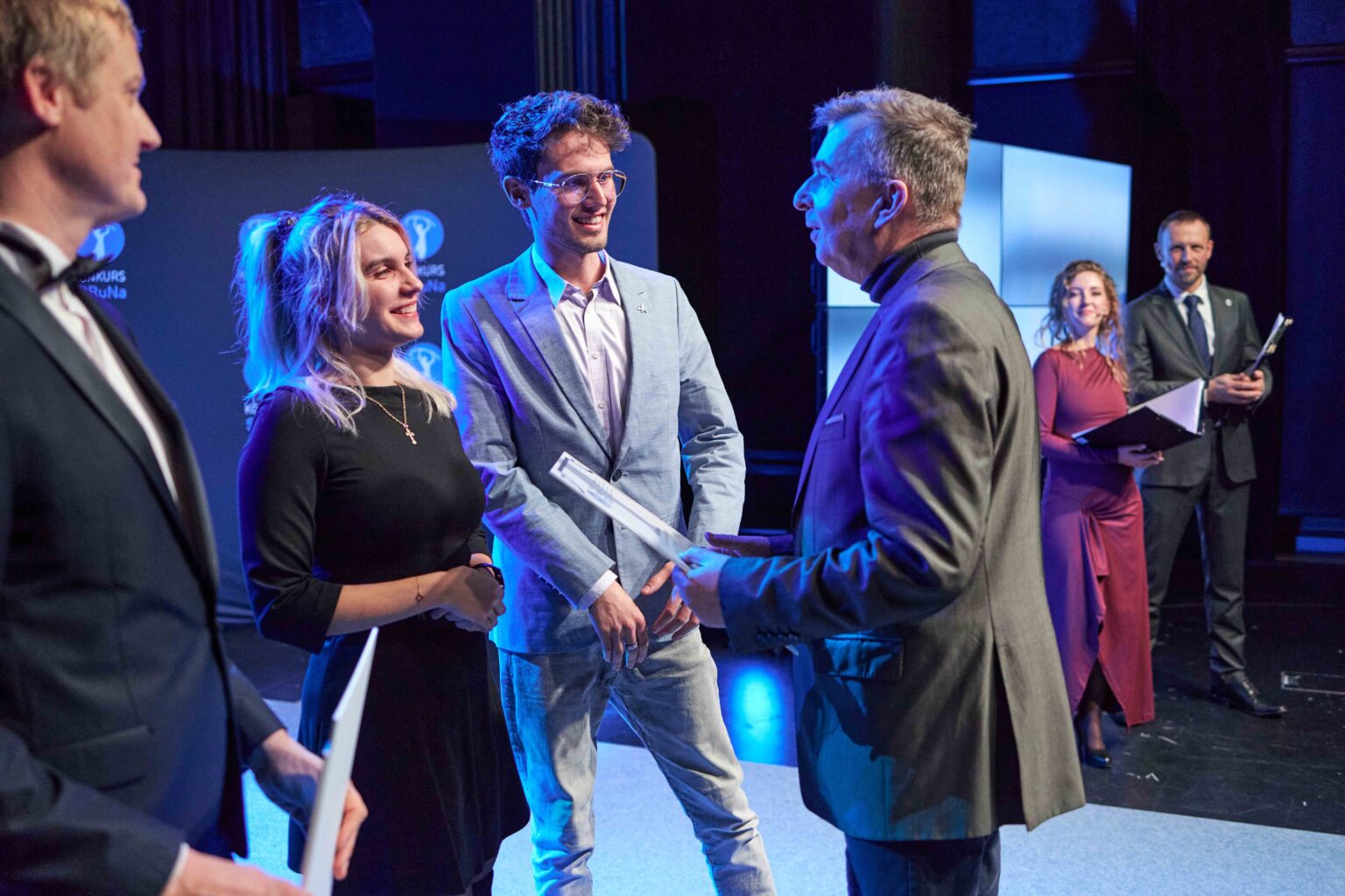 trzy osoby na scenie rozmawiają