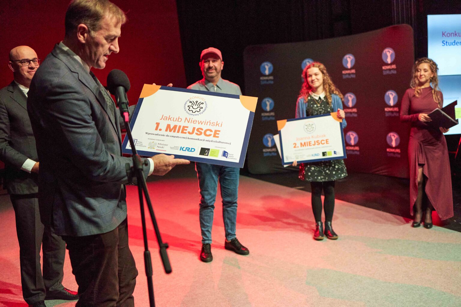 dwie osoby na scenie z dyplomami