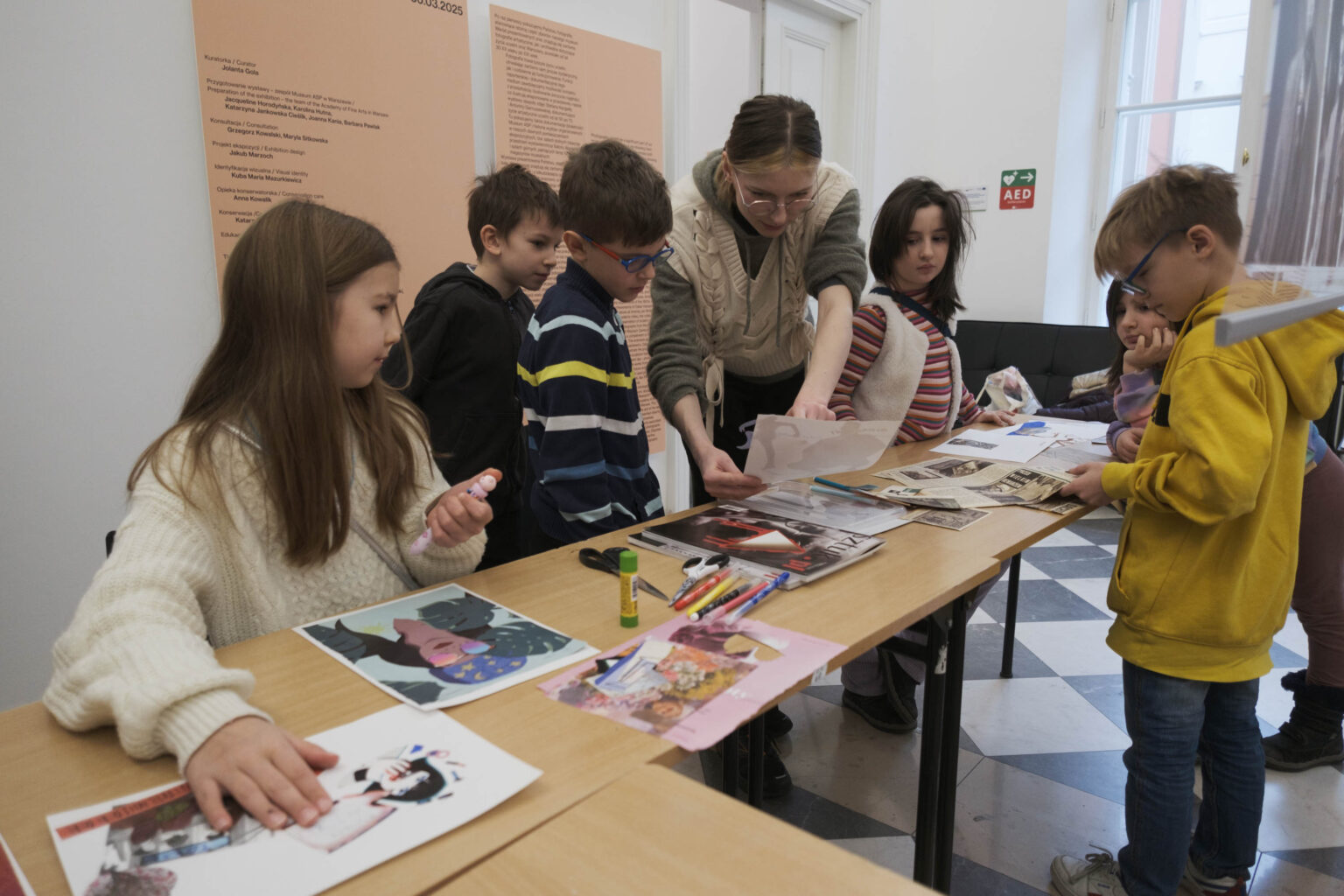 grupa dzieci i prowadząca zajęcia przy stole z materiałami plastycznymi