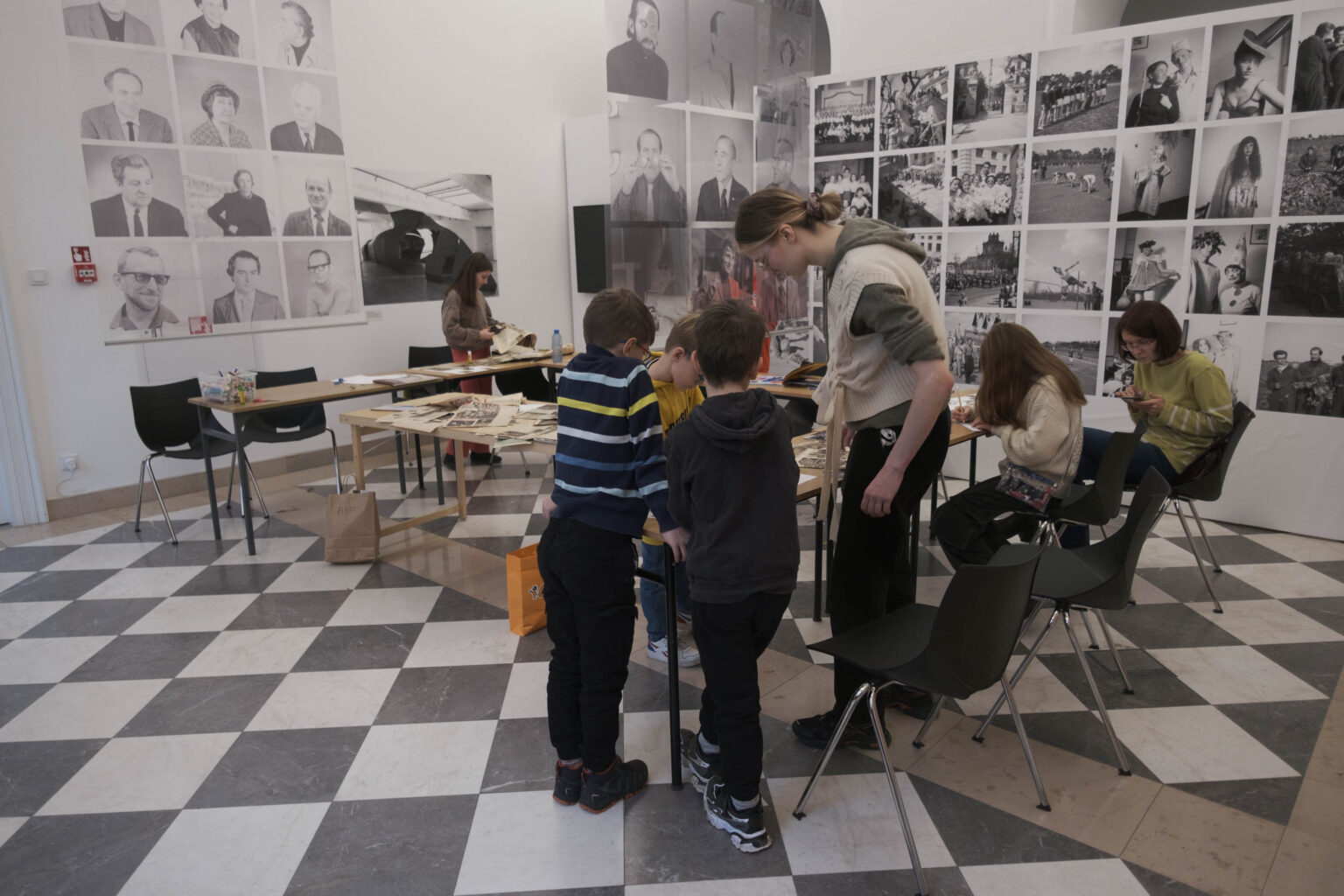 grupa dzieci i prowadząca zajęcia przy stole gazetami