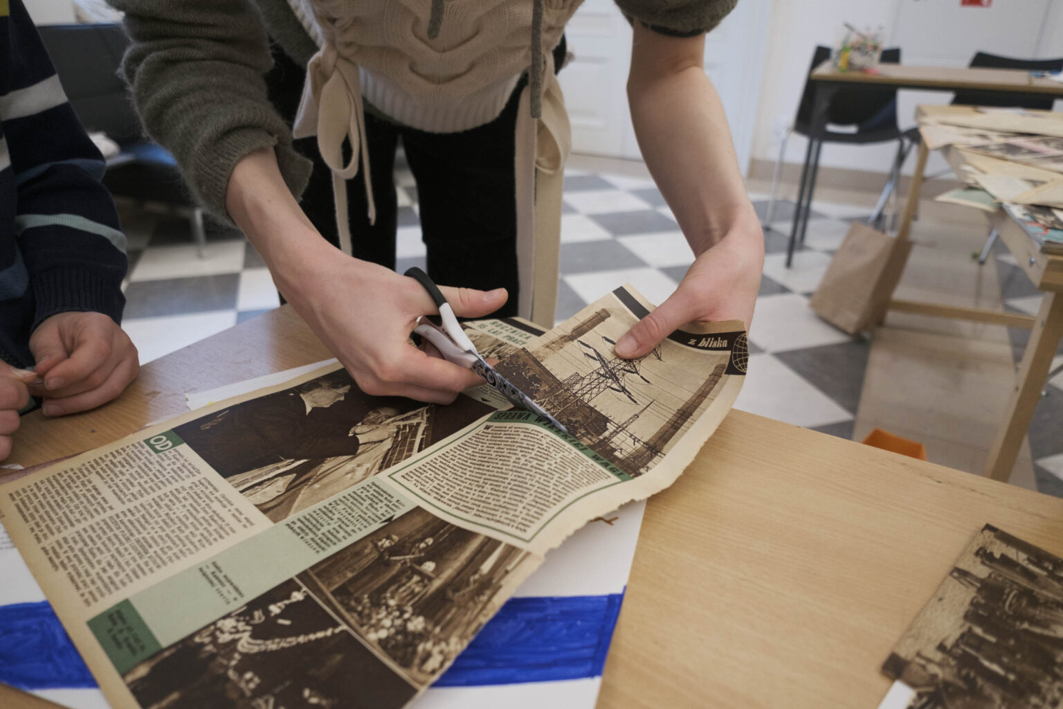 ręce kobiety tną nożyczkami starą gazetę