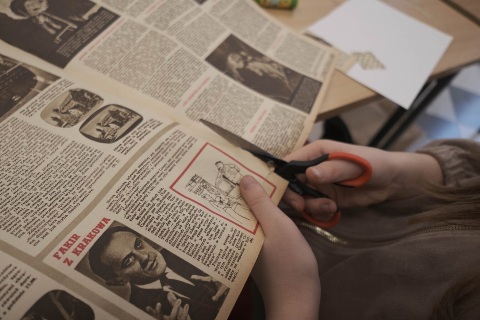 ręce dziecka trzymające nożyczki tną starą gazetę