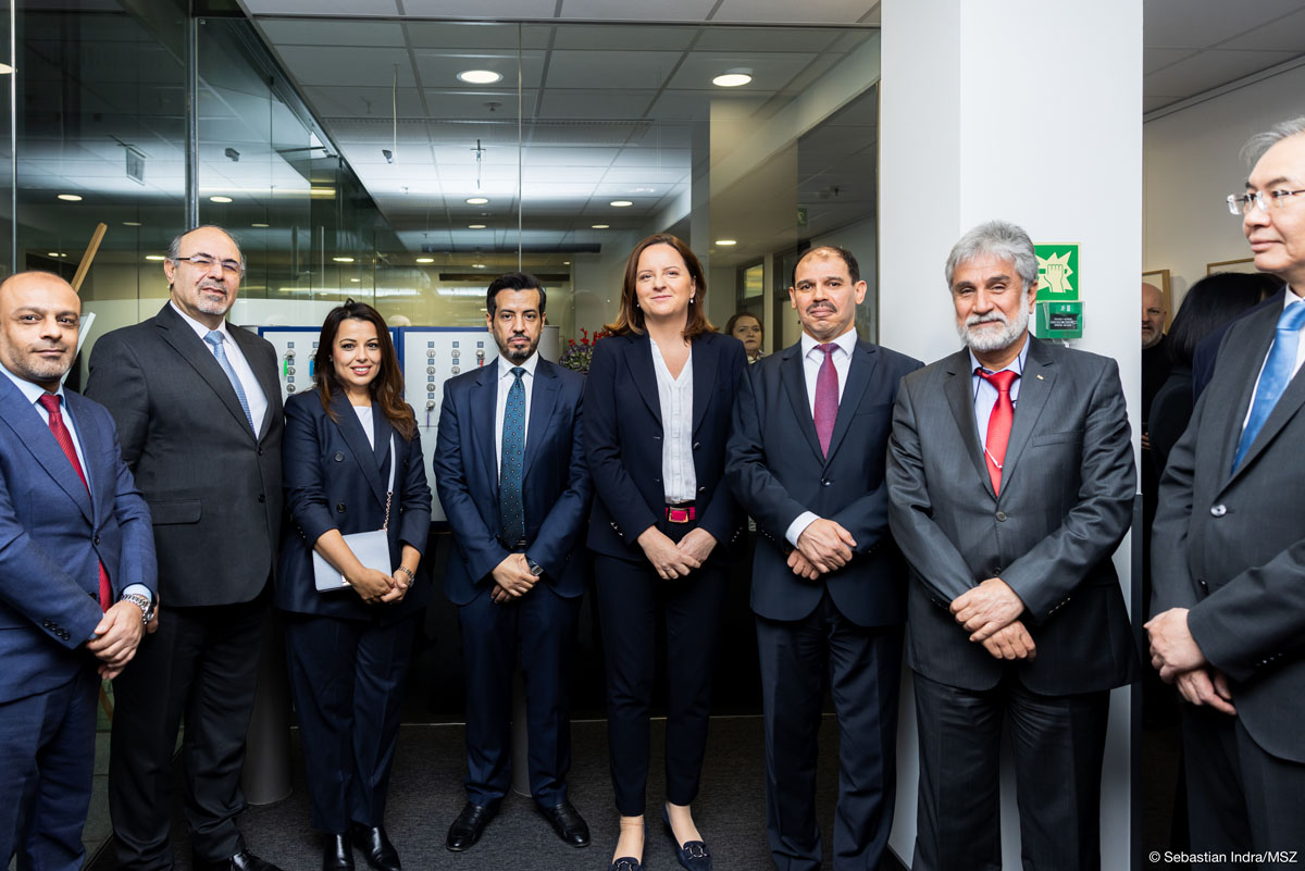 Osiem osób: dwie kobiety i sześciu mężczyzn pozuje do zdjęcia, lekko się uśmiechając, są elegancko ubrani w czarne lub ciemnogranatowe garnitury.