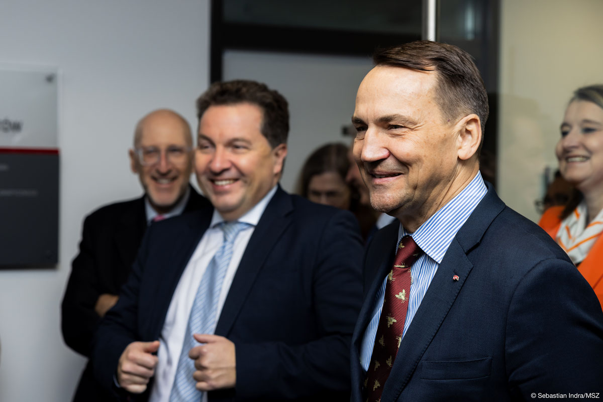 Grupa stojących razem ludzi ubranych w garnitury i krawaty