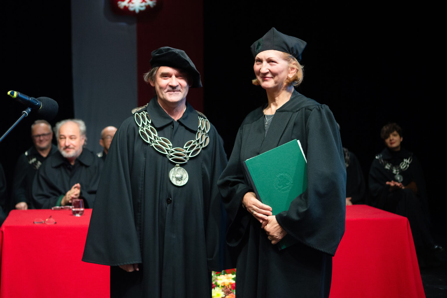 mężczyzna i kobieta w strojach reprezentacyjnym ASP w Warszawie, kobieta trzyma dyplom