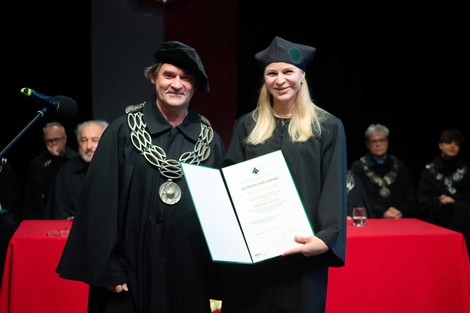 mężczyzna i kobieta w strojach reprezentacyjnym ASP w Warszawie, kobieta z dyplomem