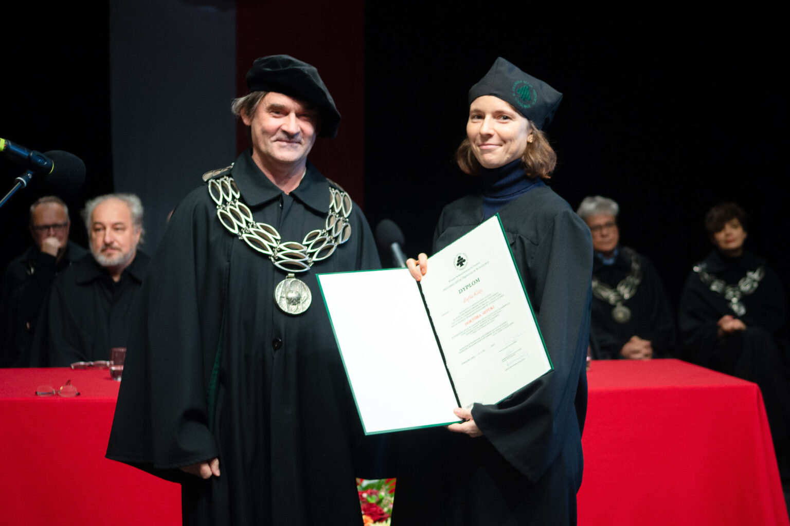 mężczyzna i kobieta w strojach reprezentacyjnym ASP w Warszawie, kobieta z dyplomem