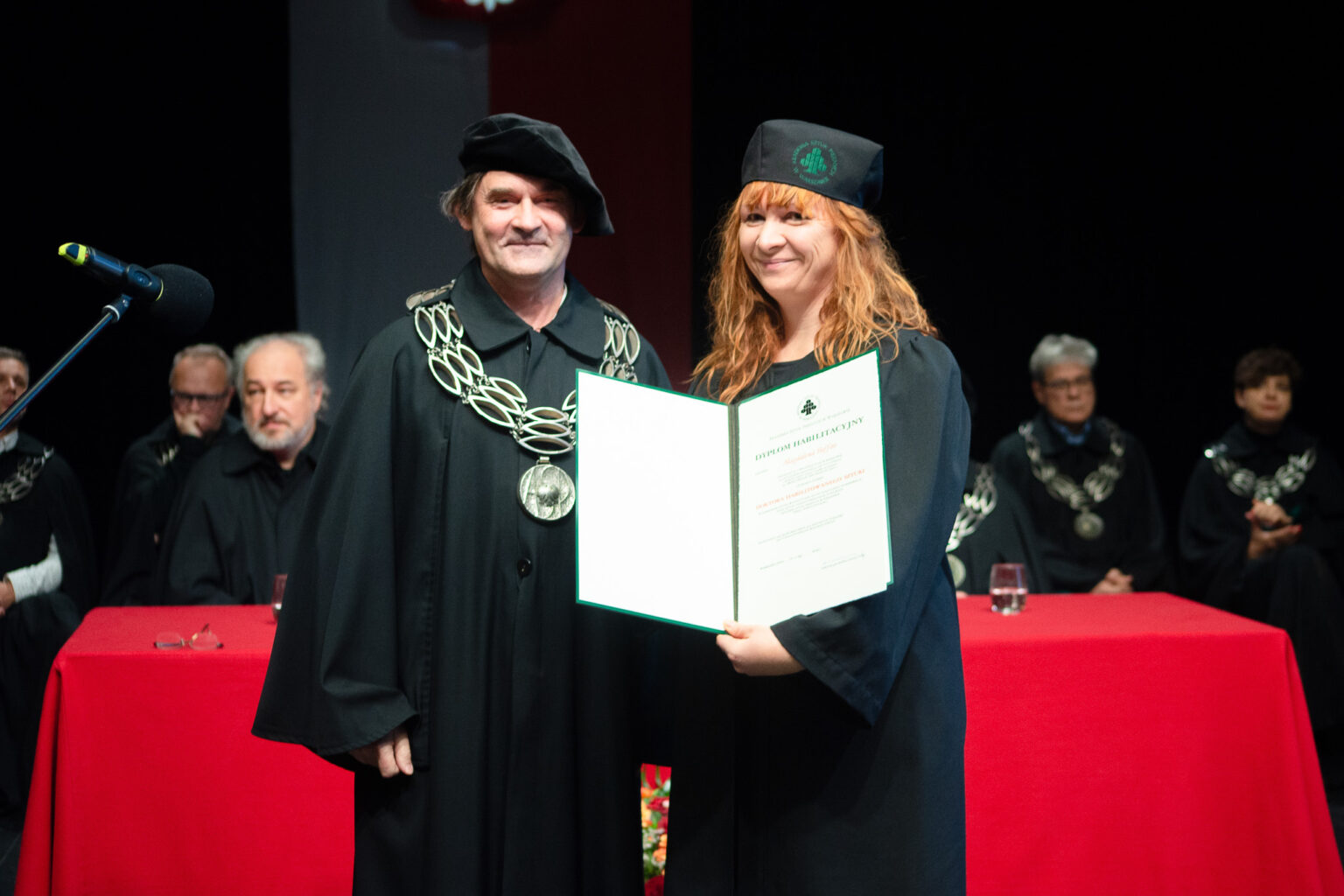 mężczyzna i kobieta w strojach reprezentacyjnym ASP w Warszawie, kobieta z dyplomem