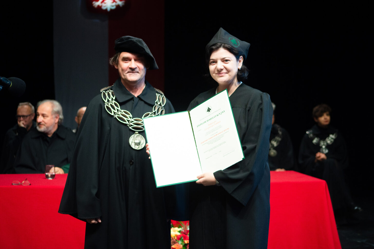 mężczyzna i kobieta w strojach reprezentacyjnym ASP w Warszawie, kobieta z dyplomem