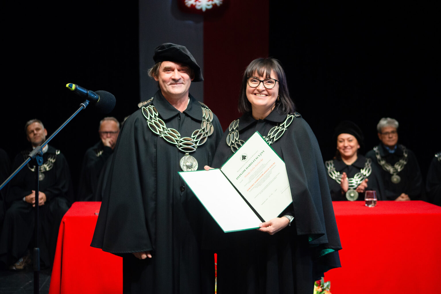 mężczyzna i kobieta w strojach reprezentacyjnym ASP w Warszawie, kobieta z dyplomem