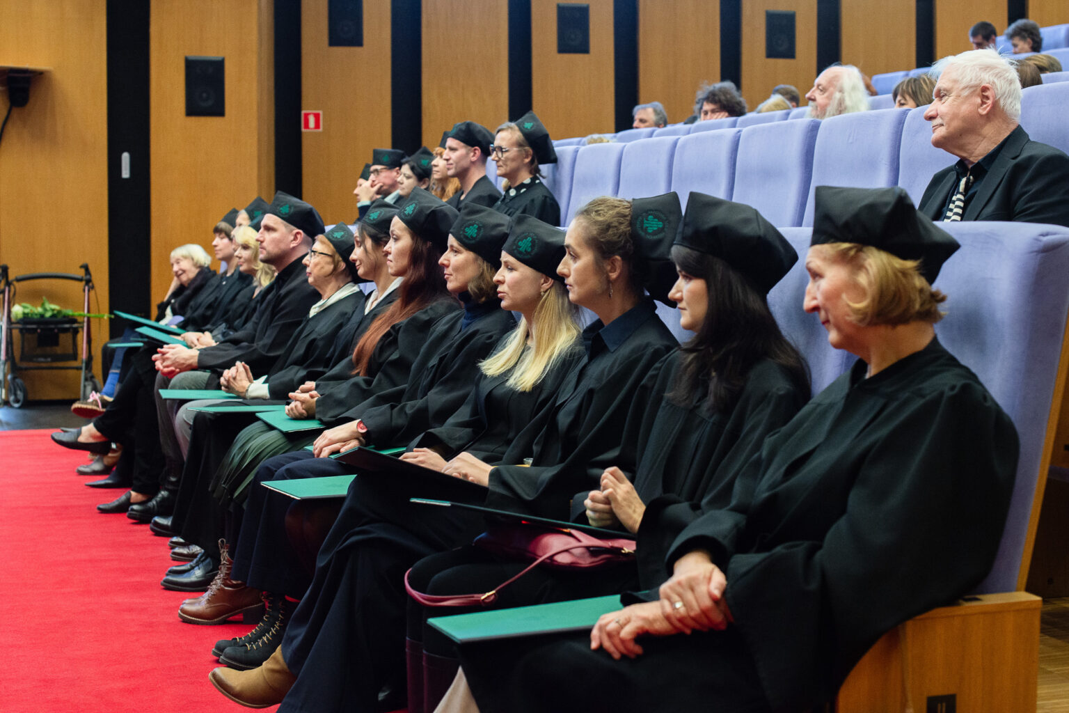 grupa osób w strojach reprezentacyjnym ASP w Warszawie na widowni