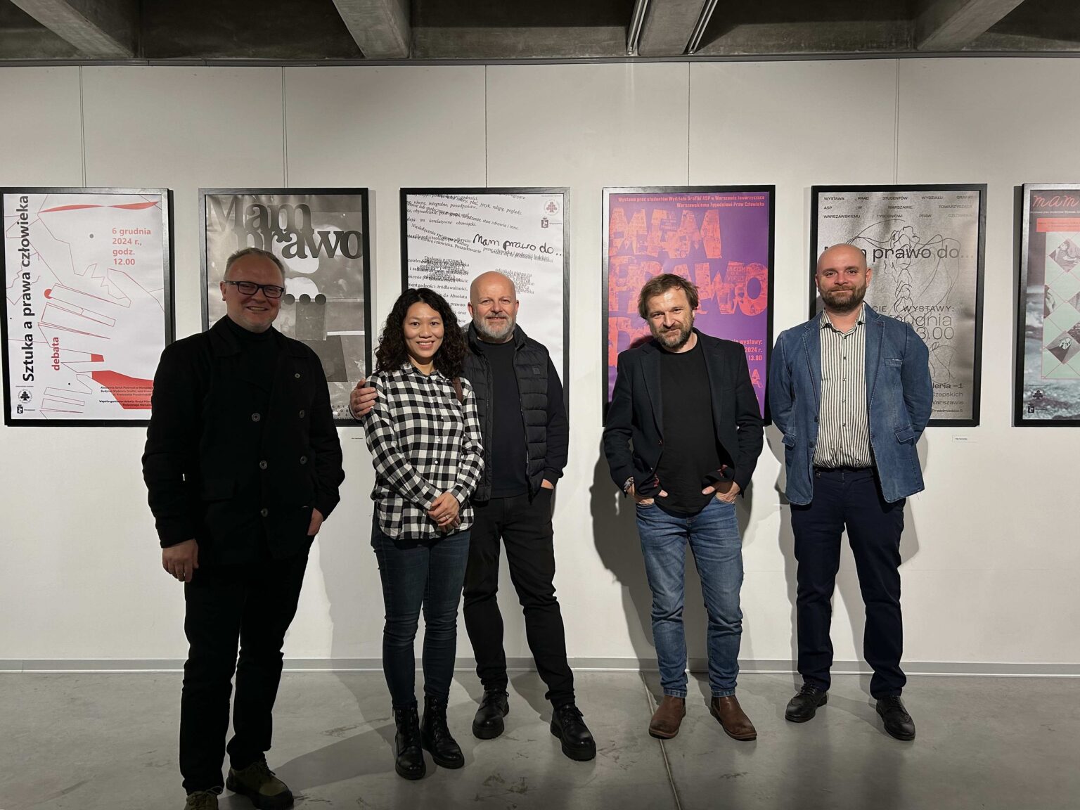 kilka osób pozuje, wystawa w tle