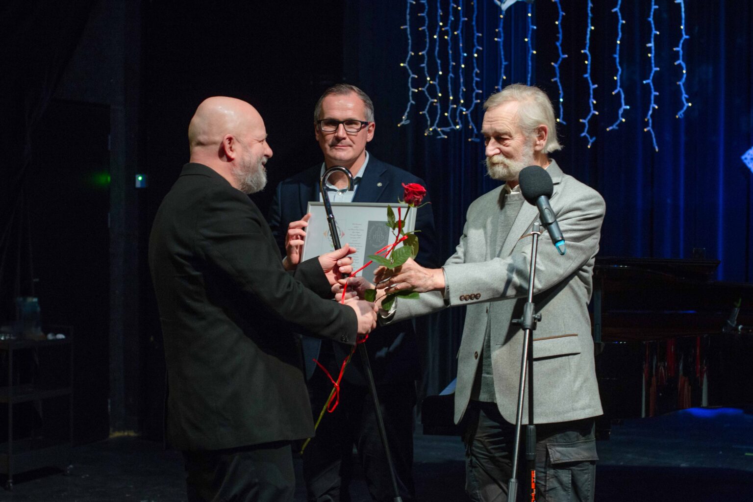 dwa j mężczyźni wręczają odznaczenie trzeciemu mężczyźnie