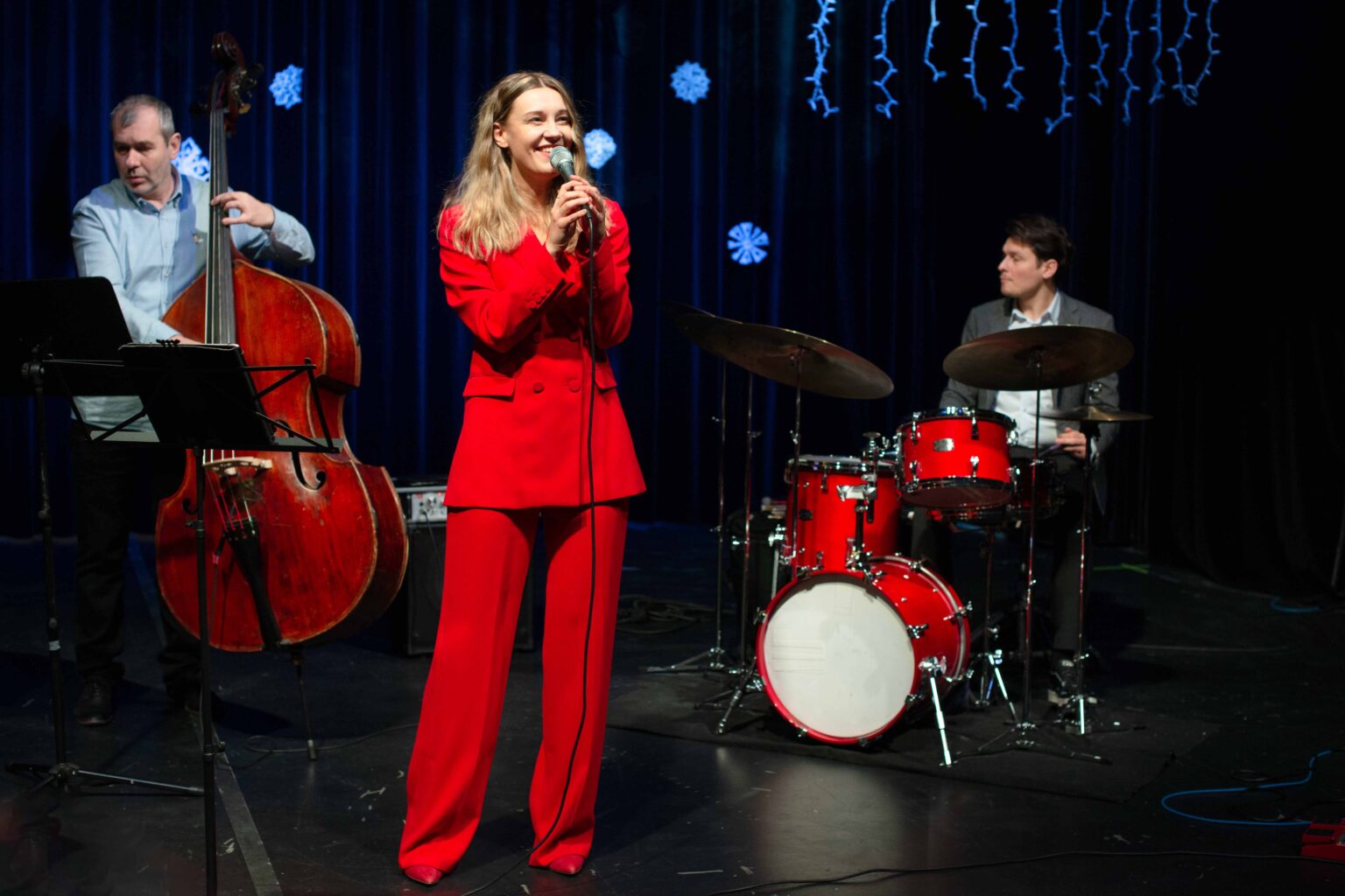 zdjęcie zespołu: kobieta w czerwonym garniturze, mężczyzna grający na kontrabasie oraz mężczyzna grający na perkusji