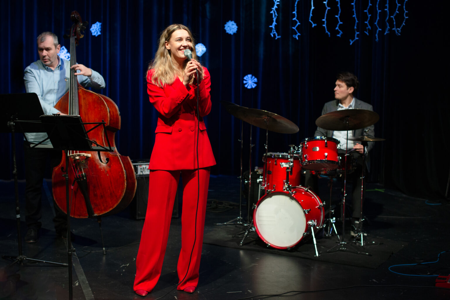 zdjęcie zespołu: kobieta w czerwonym garniturze, mężczyzna grający na kontrabasie oraz mężczyzna grający na perkusji