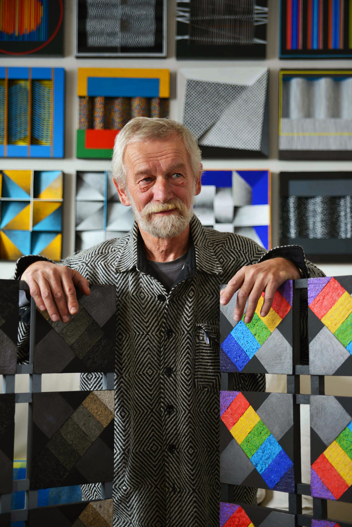 Zdjęcie mężczyzny otoczonego kolorowymi pracami