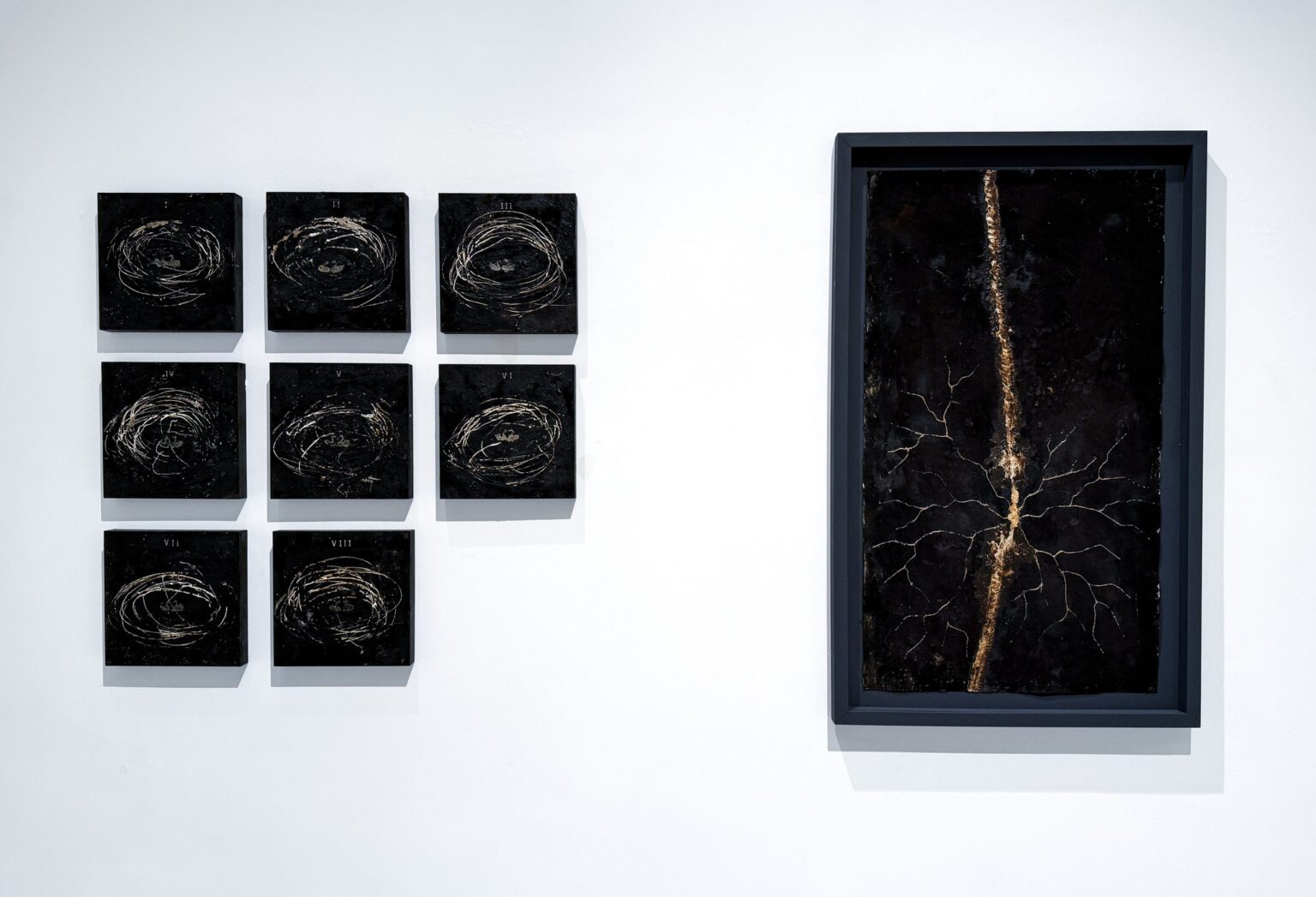 kilka małych symetrycznie powieszonyh, czarnuch obrazków, obok jeden duży, również czarnego koloru