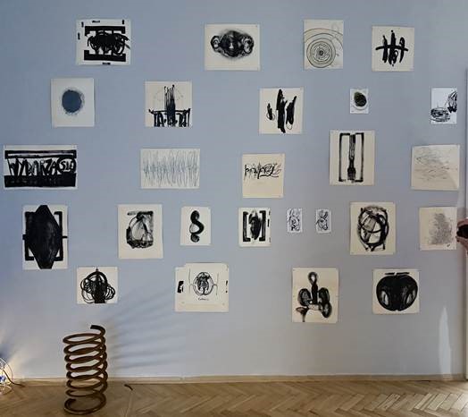 dużo czarno-białych, niewielkich rysunków na papiere wyeksponowanych na ścianie galerii