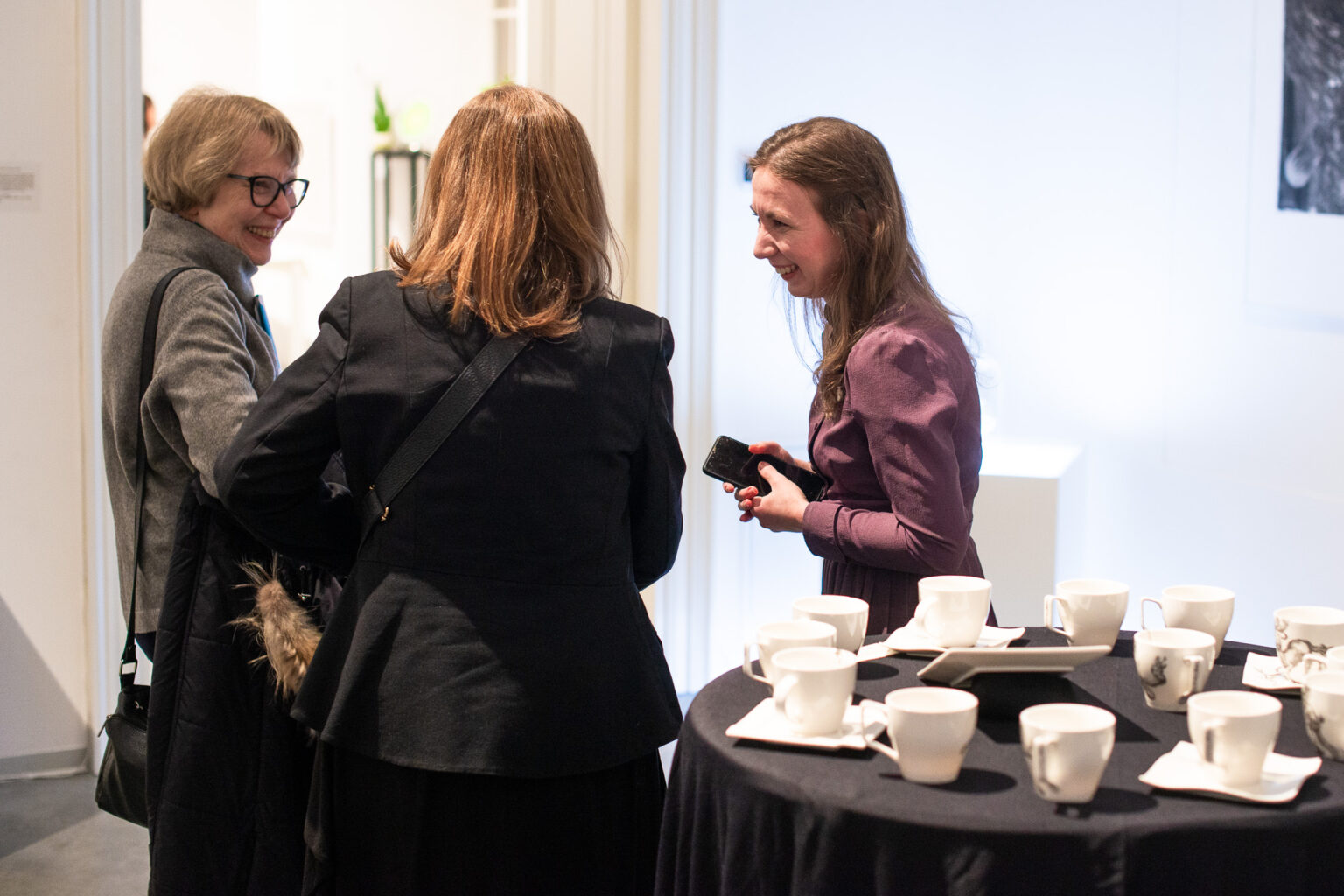 trzy uśmiechnięte kobiety, obok stół z porcelaną