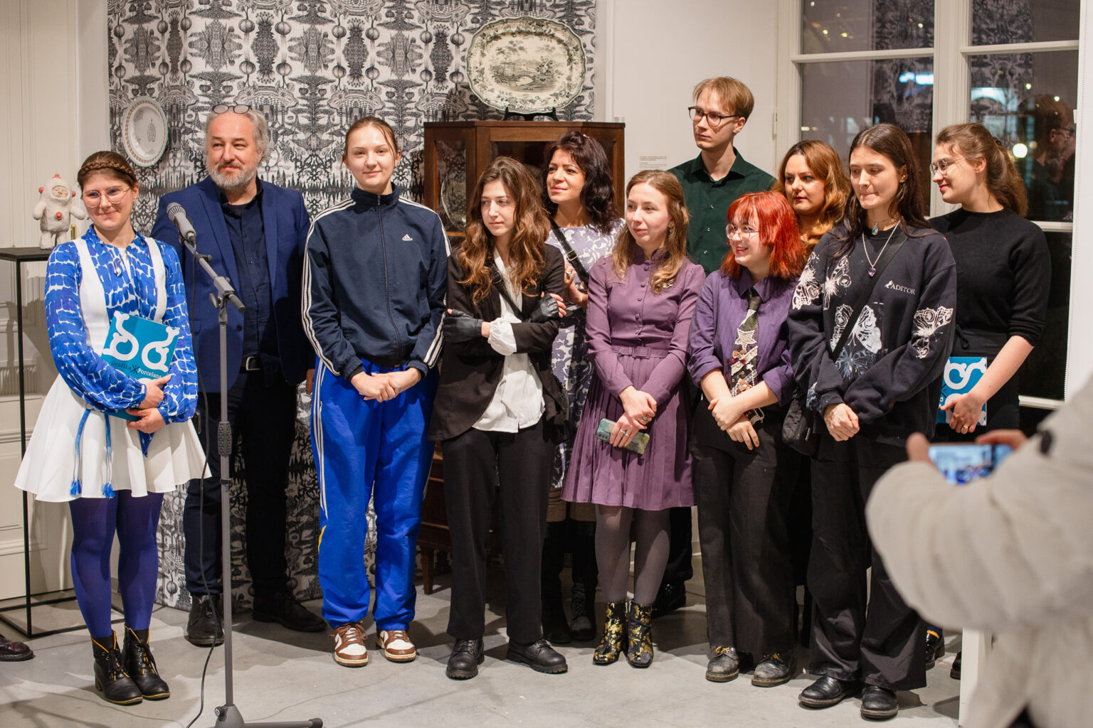 duża grupa osób przed mikrofonami, w przestrzeni wystawy