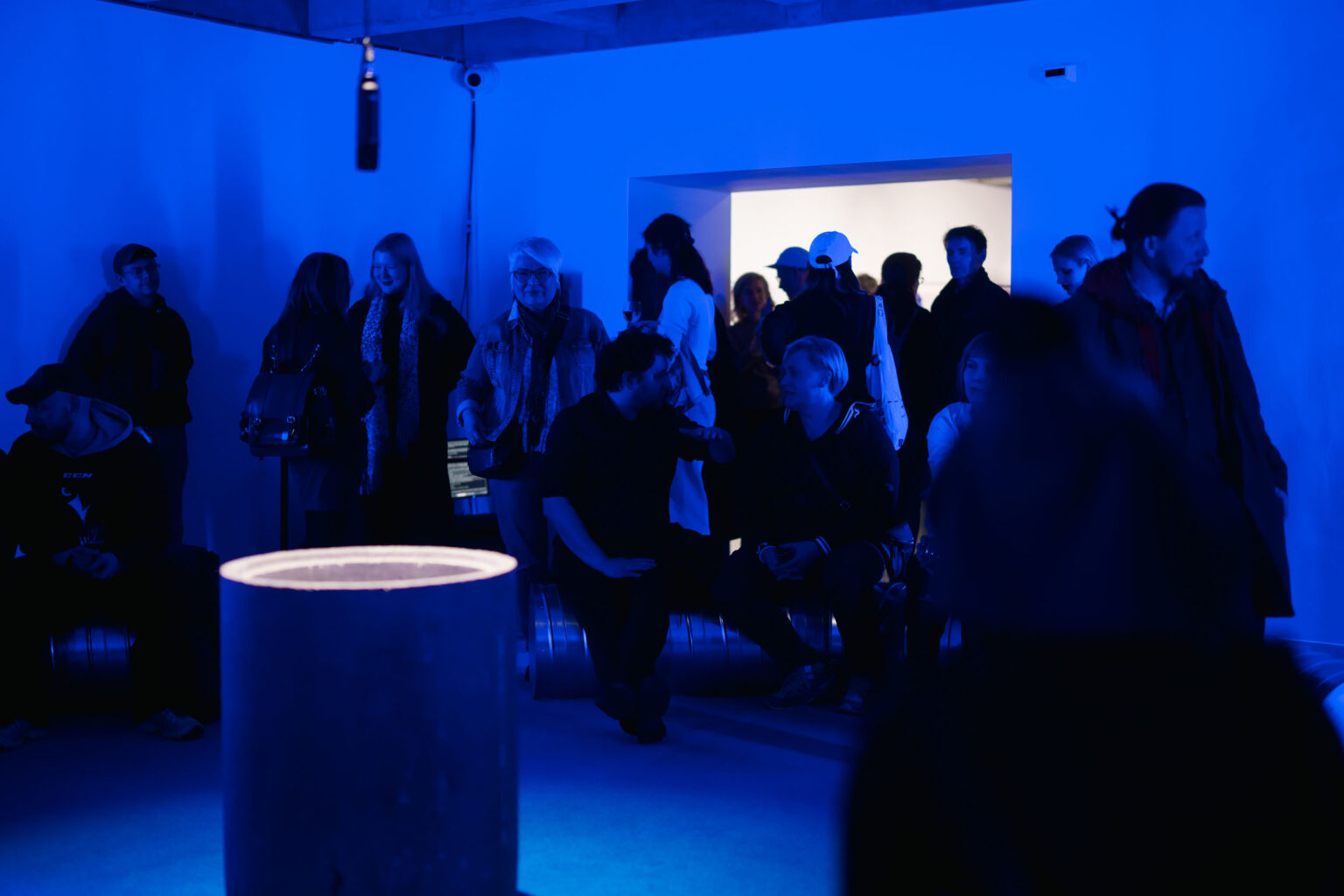 duża grupa osób w przestrzeni wystawy podświetlonej na niebiesko