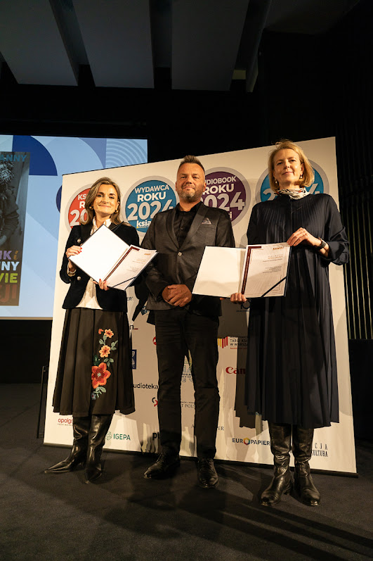 trzy osoby w rzędzie prezentują dyplomy