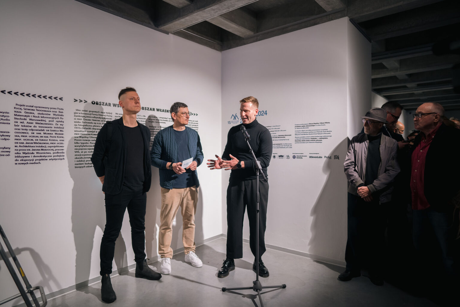 trzech mężczyzn, jeden mówi do mikrofonu