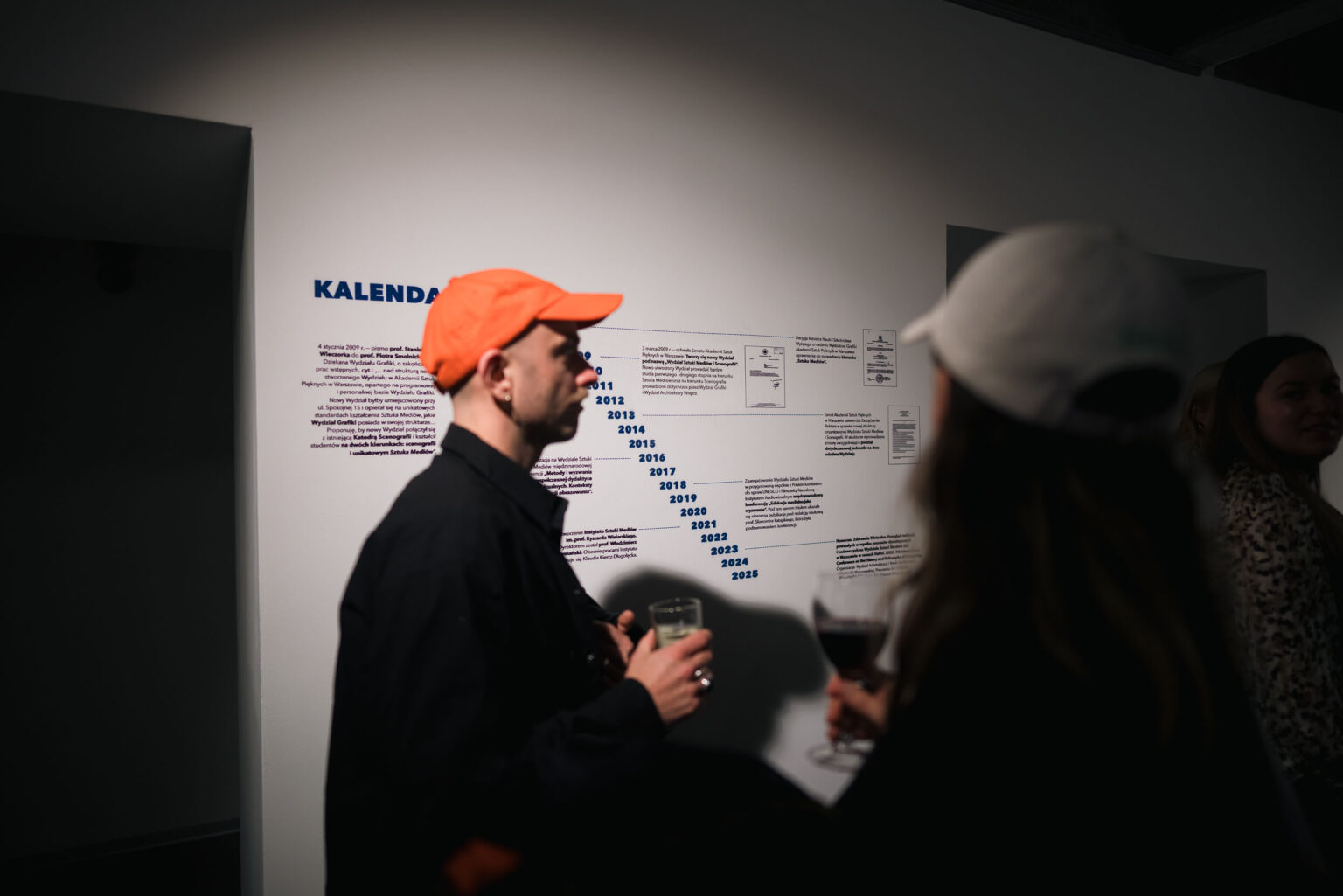 chłopak w czapce z daszkiem na tle napisów na ścianie galerii