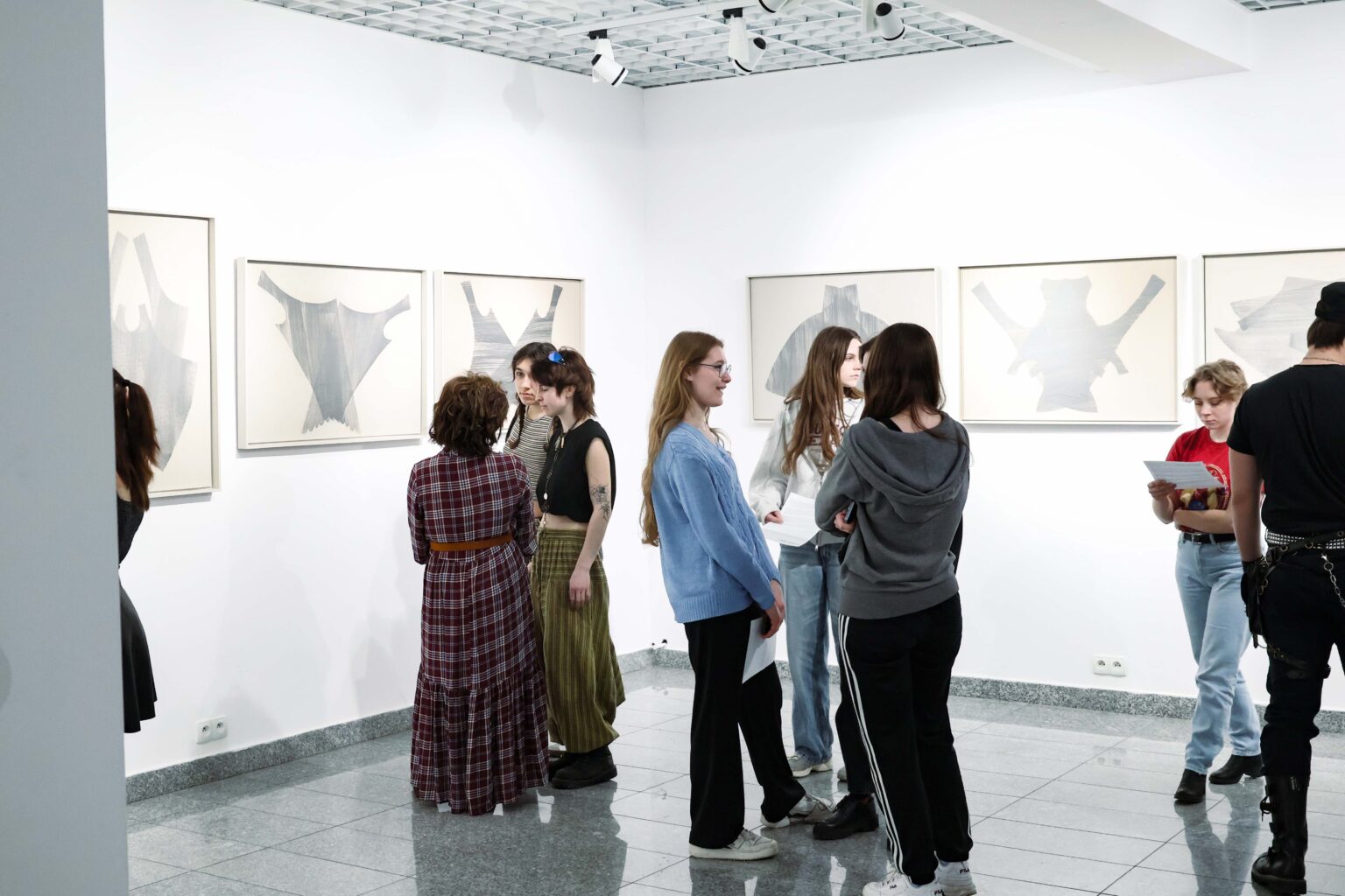 widok wystawy, kilka osób oglądających wystawę po środku