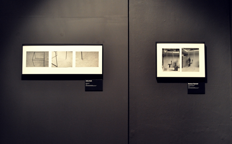 Czarna ściana, na której powieszone są dwie ramki. W ramkach na białym tle widoczne są niewielkie czarno-białe zdjęcia artystyczne