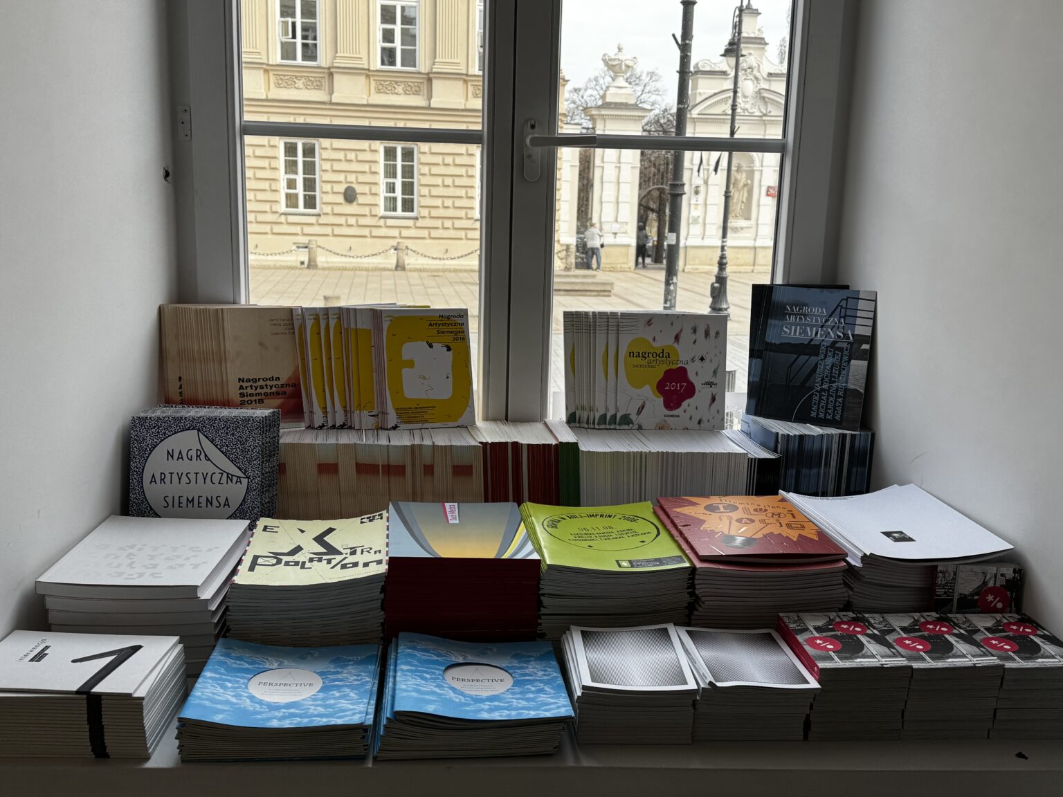 zdjęcie kolorowych książek na regale ułożonych na parapecie okiennym