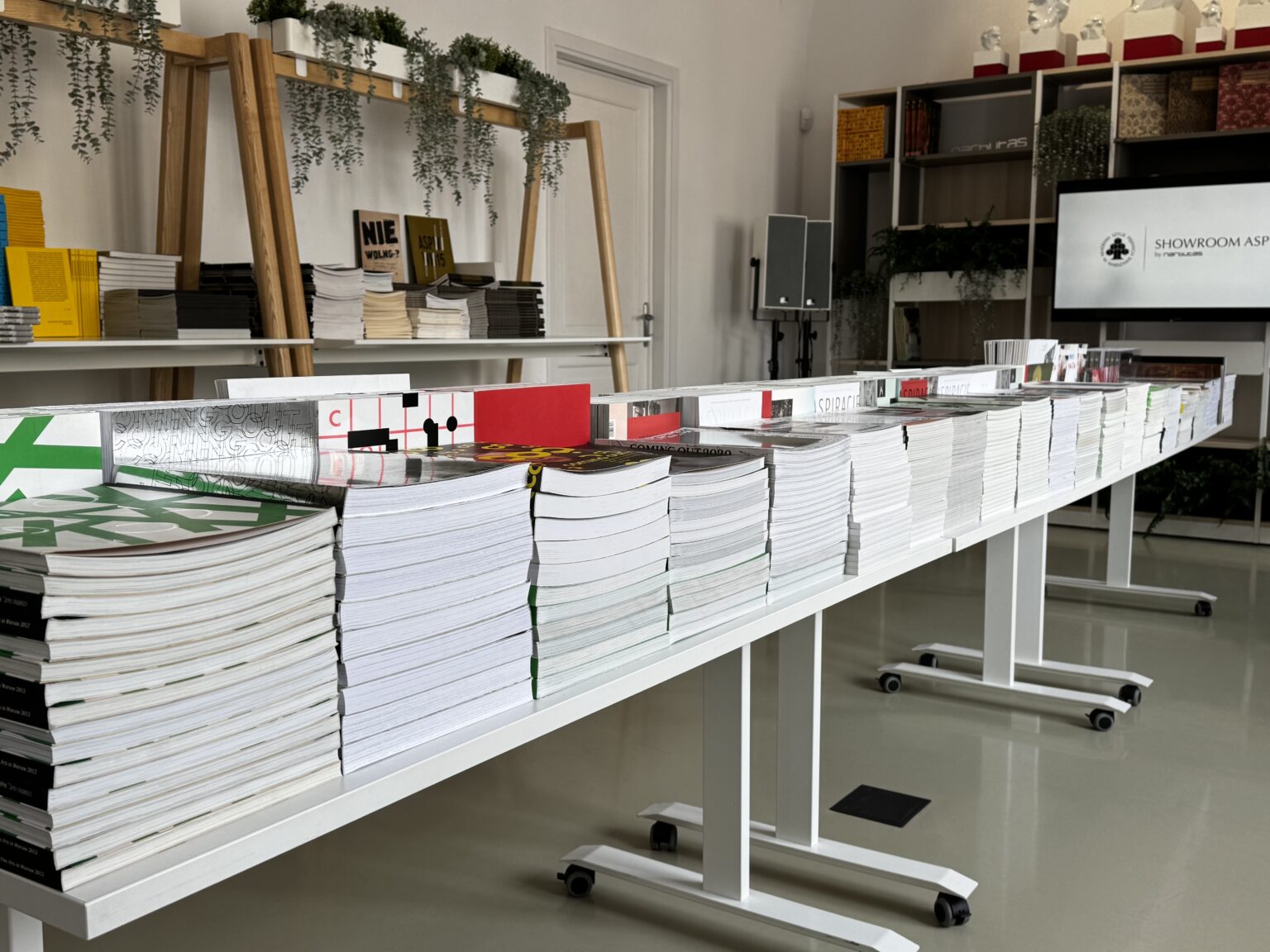 zdjęcie podłużnych białych stołów w dużą ilością poukładanych książek