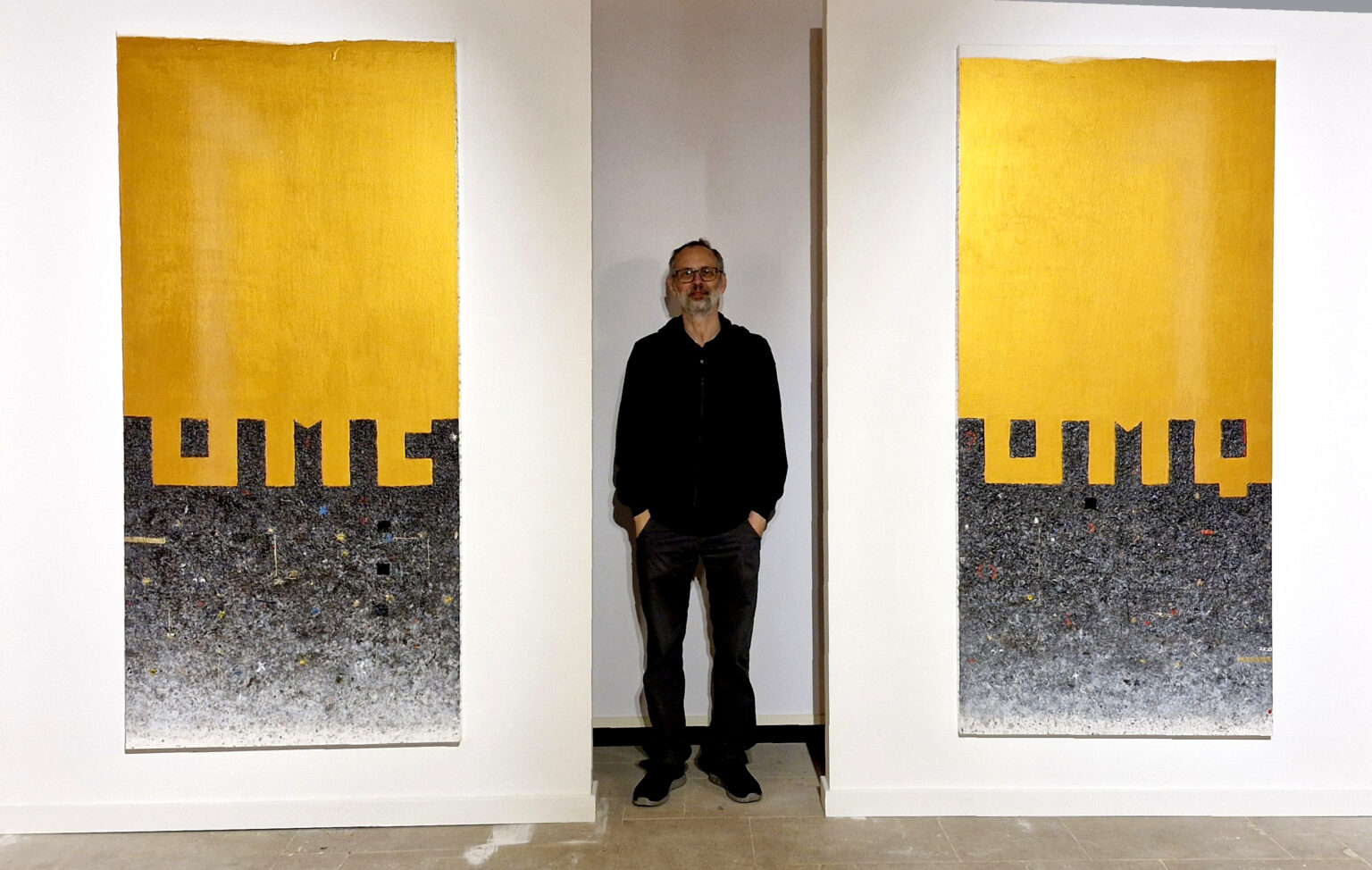 Mężczyzna stoi pomiędzy przewyższającymi do obrazami z mocnym złotym akcentem