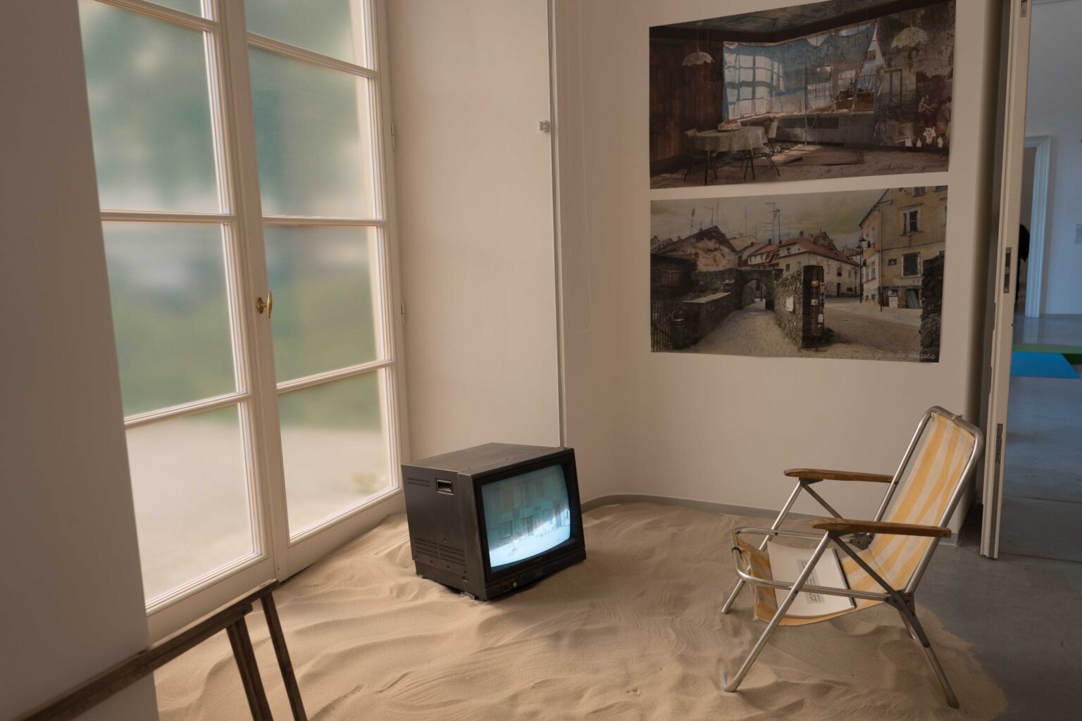 ekspozycja: obrazy na ścianie, na podłodze: piasek, telewizor, fotel rozkładany