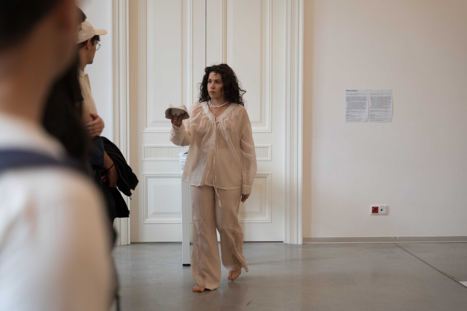 grupa osób, kobieta w białym stroju podaje im białe naczynie