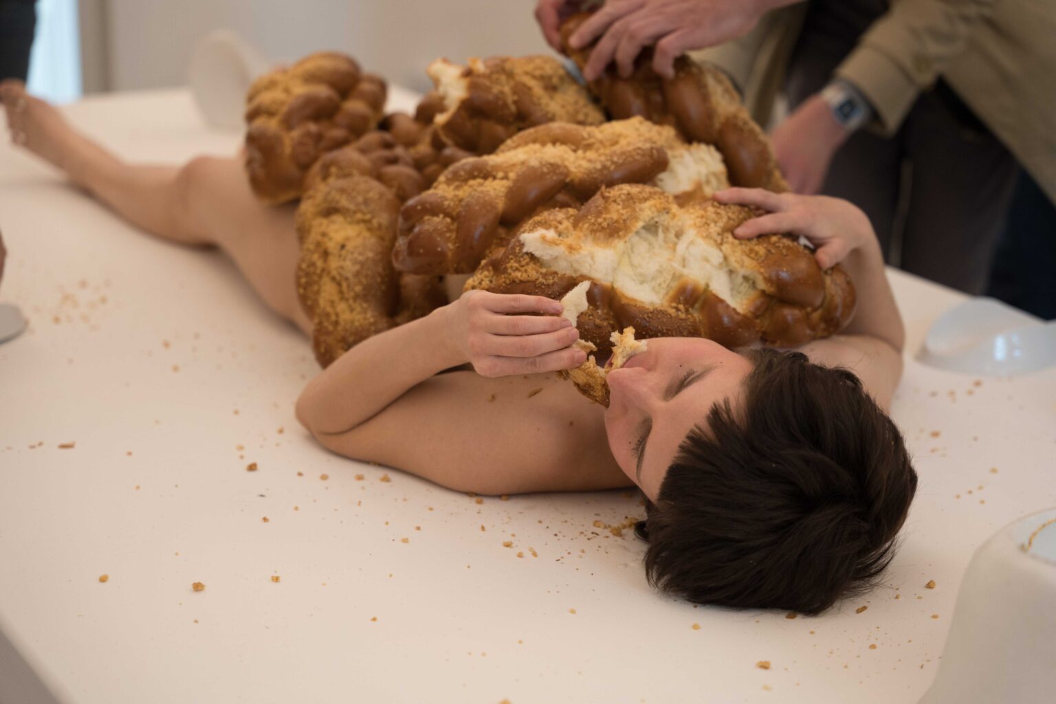 naga kobieta leży na białym stole, na niej sterta chałek