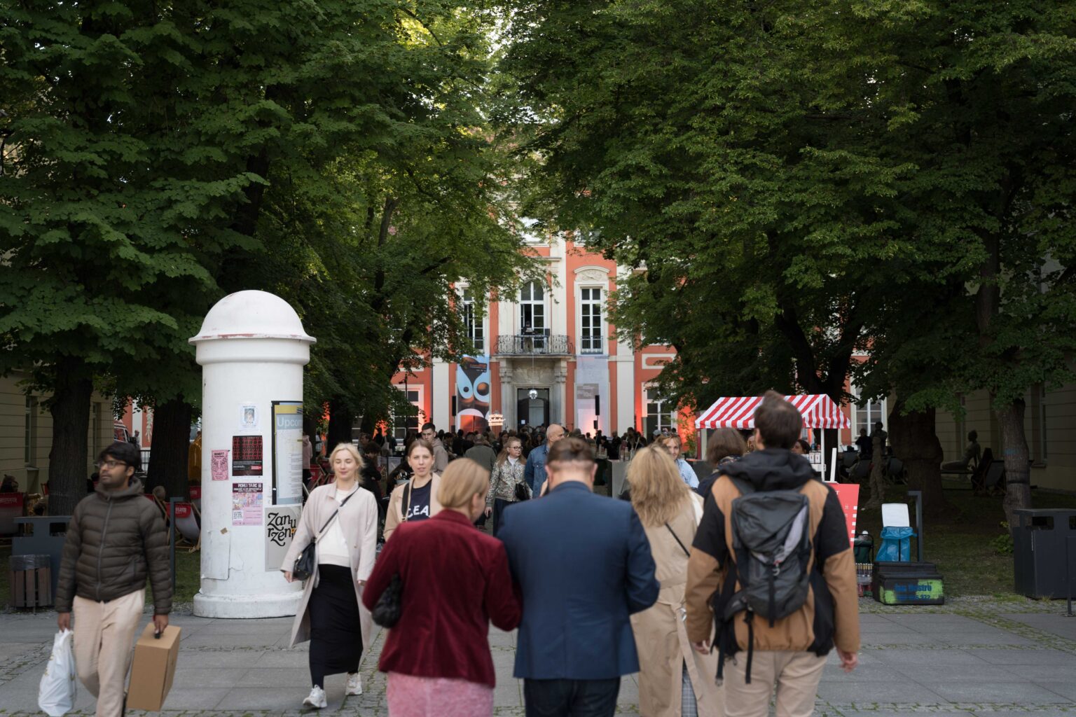 duża grupa osób idzie w kierunku pałacu w kolorze czerwonym