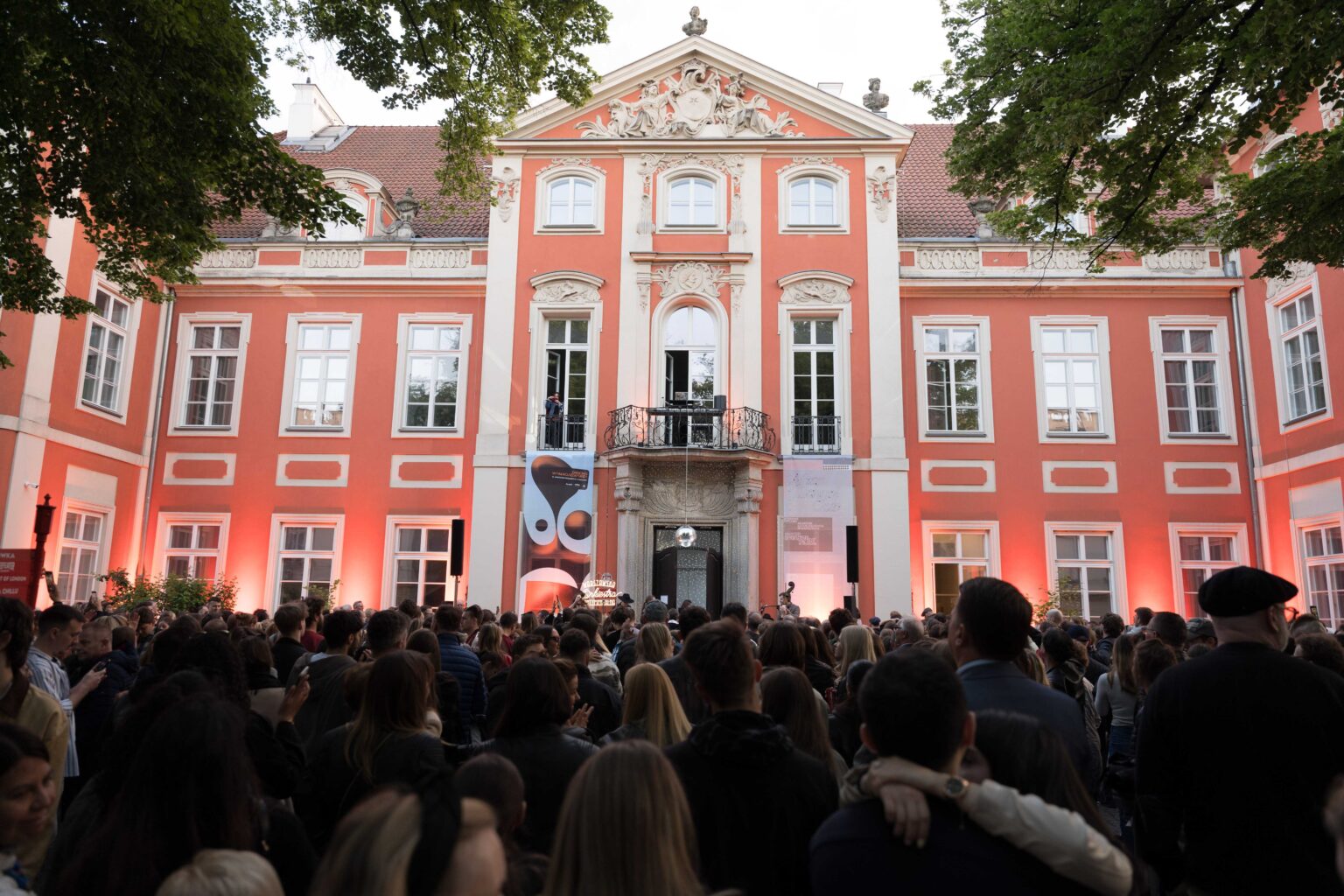 tłum ludzi, w tle pałac w czerwonym kolorze