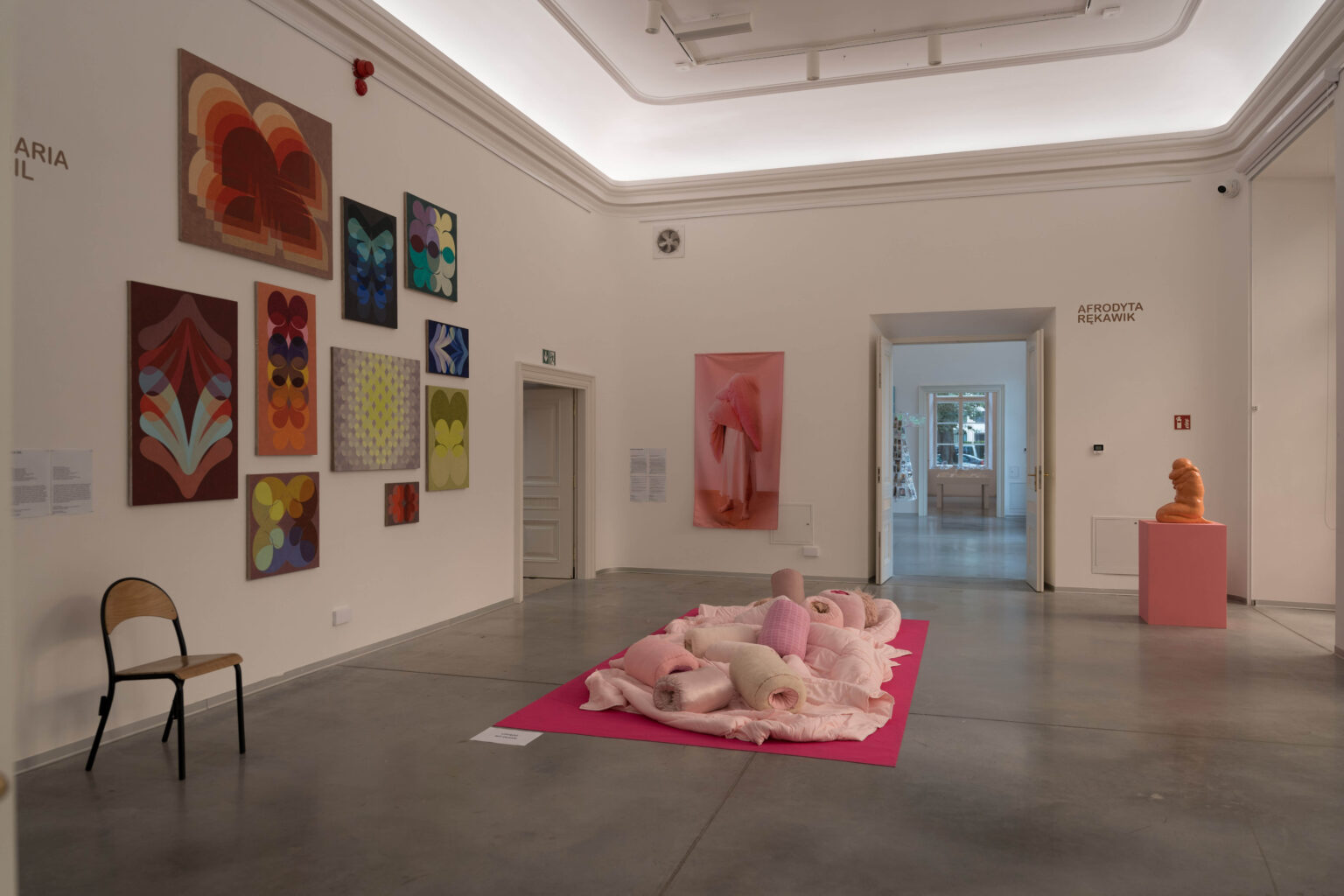różowe miękkie obiekty przypominjące poduch na podłodze w przestrzeni wystawy