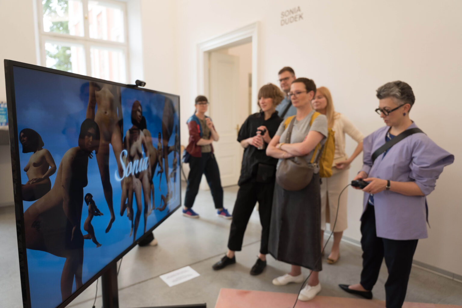 grupa osób przed ekranem z grą